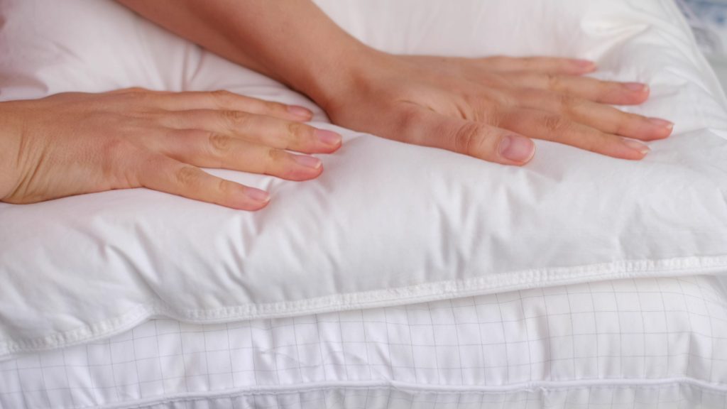 manos de mujer joven tocando relleno de la almohada
